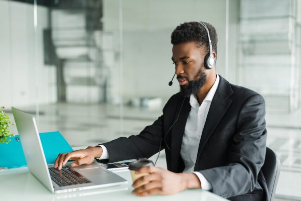 African american customer support operator with hands-free headset working in the office.