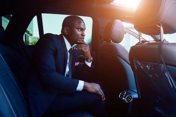 Handsome, successful rich african american businessmen in a stylish black business suit and tie sitting in a luxury car. concept of luck and career growth